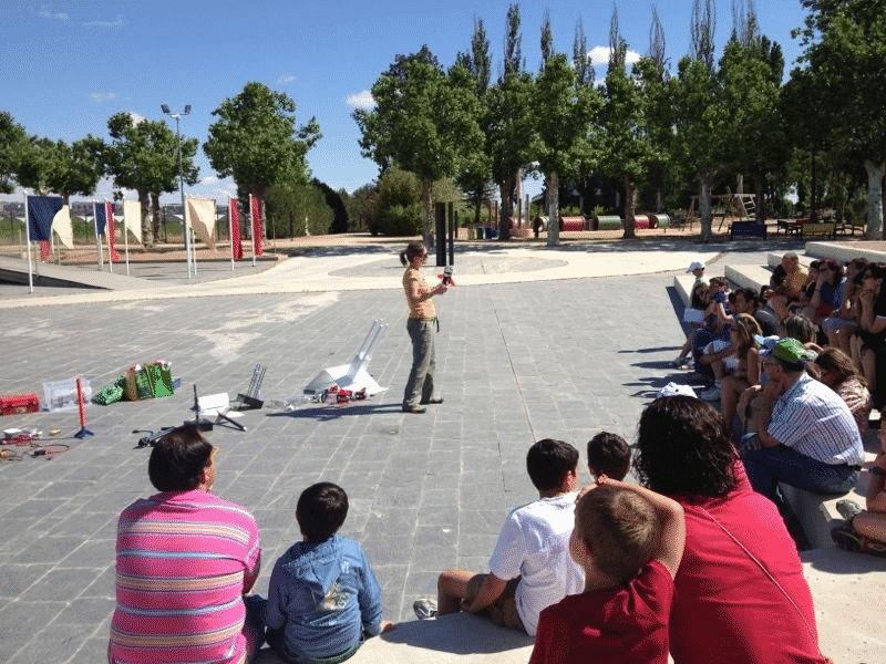 Taller de divulgación científica al aire libre con público sentado alrededor