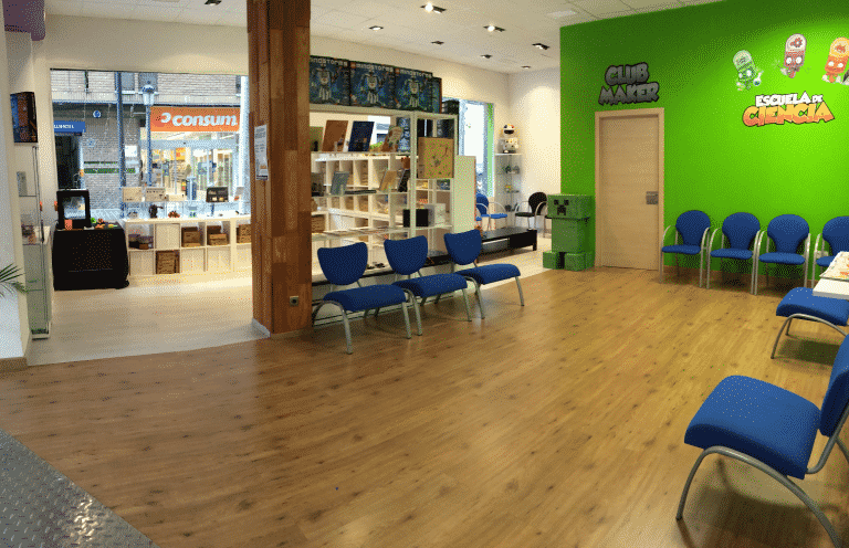 Sala de espera del centro Escuela de Ciencia con sillas azules y pared verde